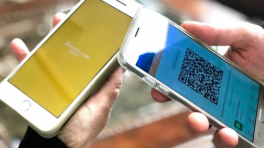 Смартфоны с экранами криптокошельков и QR-кодом для перевода (иллюстрация)