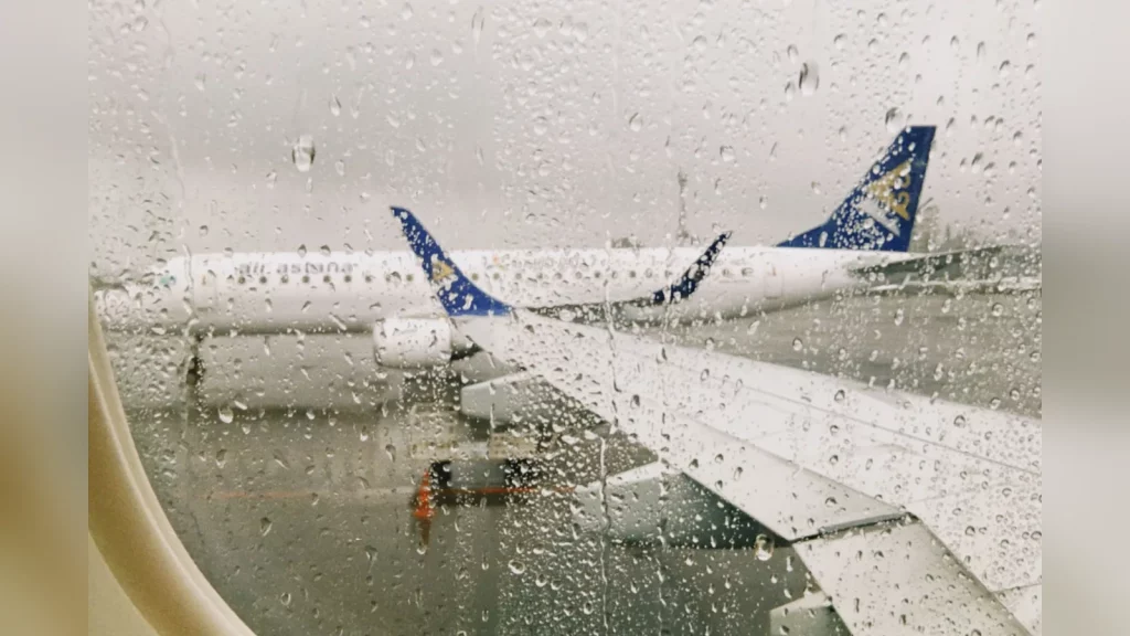 An Air Astana aircraft on the apron at Almaty Airport, with a ground crew member nearby. Documentary photograph in natural light, with no text.