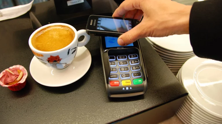 Банктік POS-терминал арқылы смартфонмен жанасусыз төлем жасау (иллюстрация)
