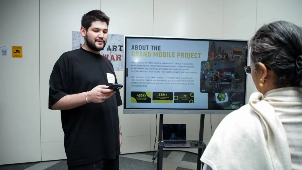 Основатель и CEO Grand Mobile Роман Линейцев на презентации игры с экраном метрик