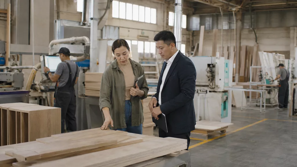 Furniture manufacturing founder discussing credit parameters with financial consultant Manufacturing business proprietor reviewing investment credit documents with a commercial finance advisor