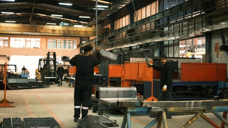 A foreign specialist and a Kazakhstani colleague working together at equipment on a factory floor in Kazakhstan. A candid moment at work, with no text.