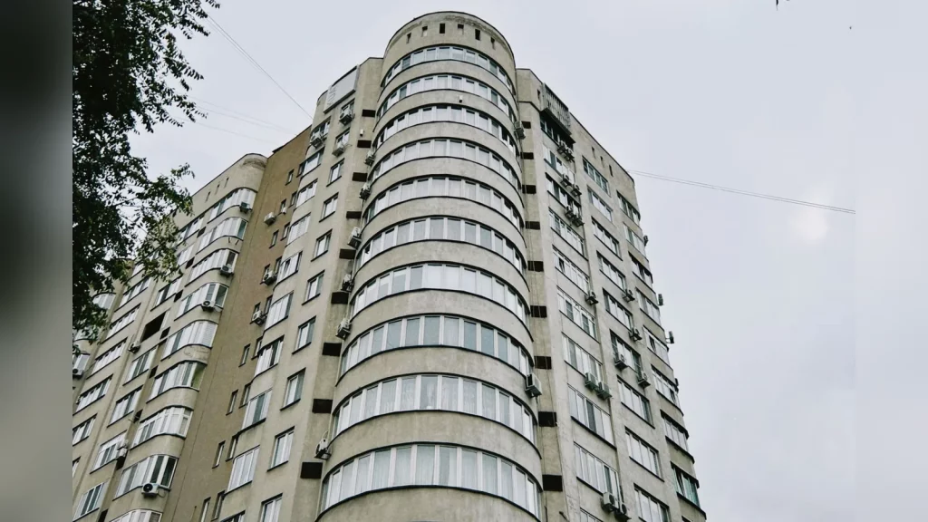 Живая сцена в квартире в Казахстане: человек готовит жильё к приезду гостей, поправляет постель, рядом лежат чистые полотенца и ключи. Обычный жилой интерьер, естественный свет, без текста.