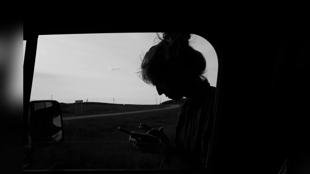 A person holding a smartphone at a roadside stop in Kazakhstan, with the steppe in the background. Natural light, documentary style, with no text or invented Rylis interface.