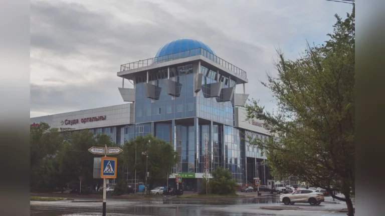 A shopper carrying bags in a shopping centre in Kazakhstan, with a lively scene outside the stores, natural lighting and no text.